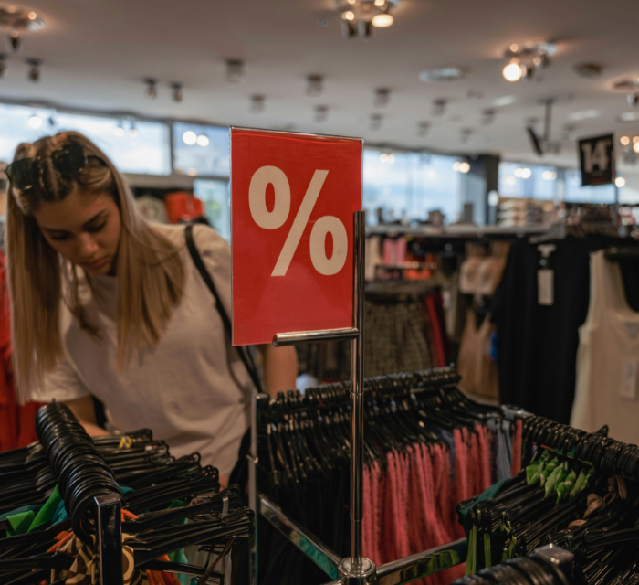 Zimowe wyprzedaże w galerii handlowej – czerwone etykiety z rabatami na swetrach i płaszczach.