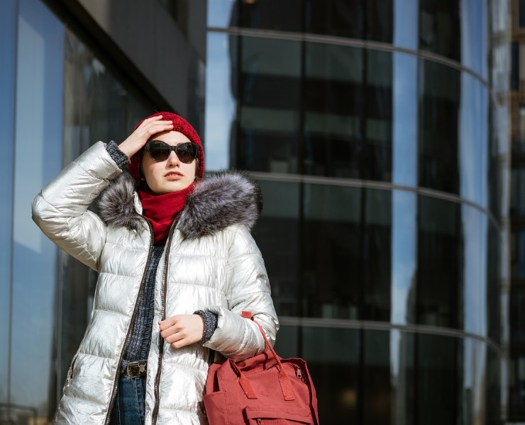 Modelka idąca ulicą w miejskiej stylizacji z jasną kurtką puchową.